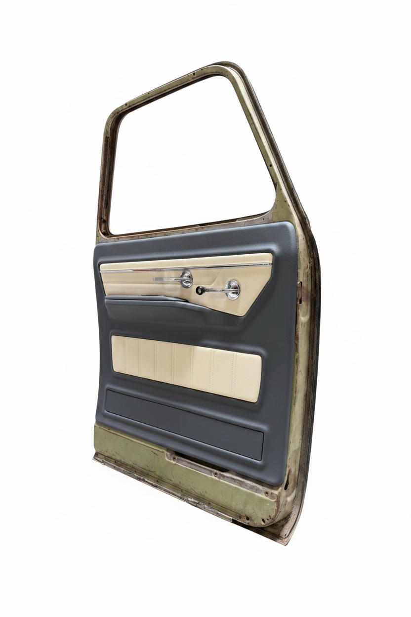 A used vintage car door panel with a dark gray vinyl outer frame, beige woodgrain trim, and chrome door handle and lock hardware, photographed inside a garage.