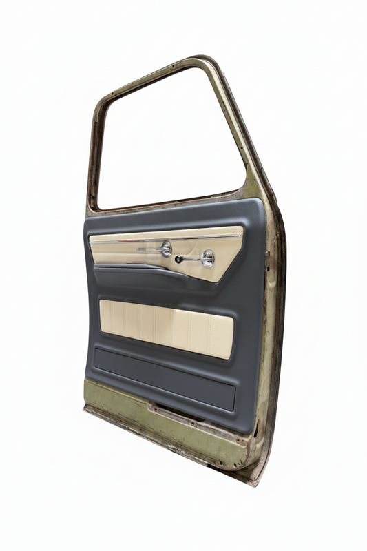 A used vintage car door panel with a dark gray vinyl outer frame, beige woodgrain trim, and chrome door handle and lock hardware, photographed inside a garage.